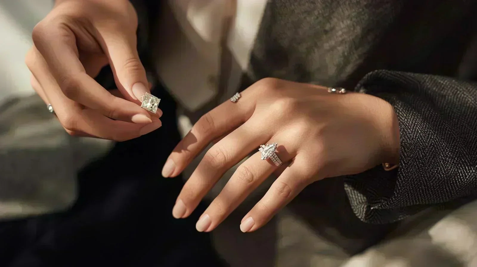 Close-up of hands holding a large princess cut lab-grown diamond and wearing a marquise cut diamond ring